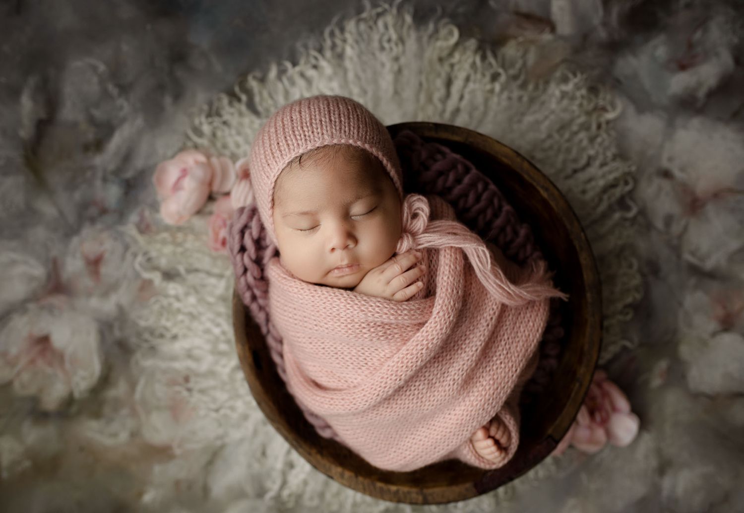 Eden Prairie newborn photographer | newborn-girl-in-pink-knitted-wrap-matching-bonnet-in-wooden-bowl-on-flower-drop