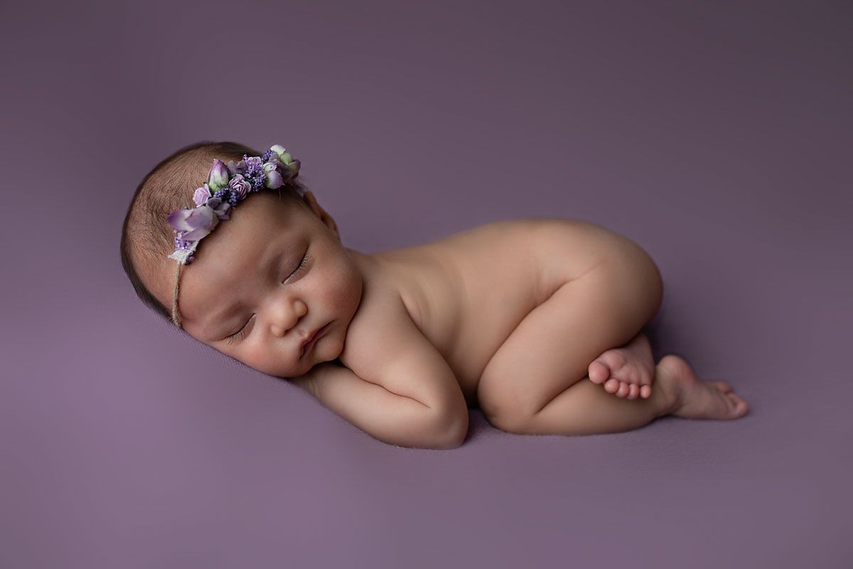 Eden Prairie newborn photographer | posed-newborn-baby-with-purple-flowered-headband-on-purple-blanket