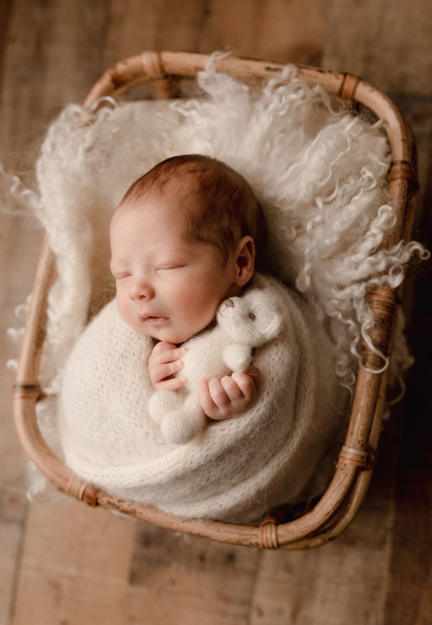 Eden Prairie newborn photographer | newborn-in-basket-with-white-fur-wrapped-in-knitted-wrap-holding-teddy-bear