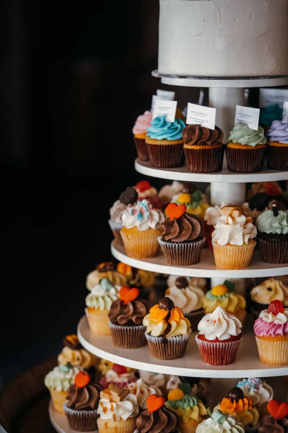 Tiered display of colorful cupcakes with various frostings and decorative toppings.