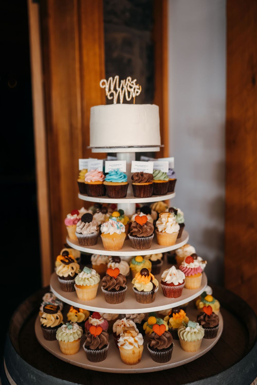 Wedding cupcake tower with white top cake and Mr & Mrs topper surrounded by decorated mini cupcakes.