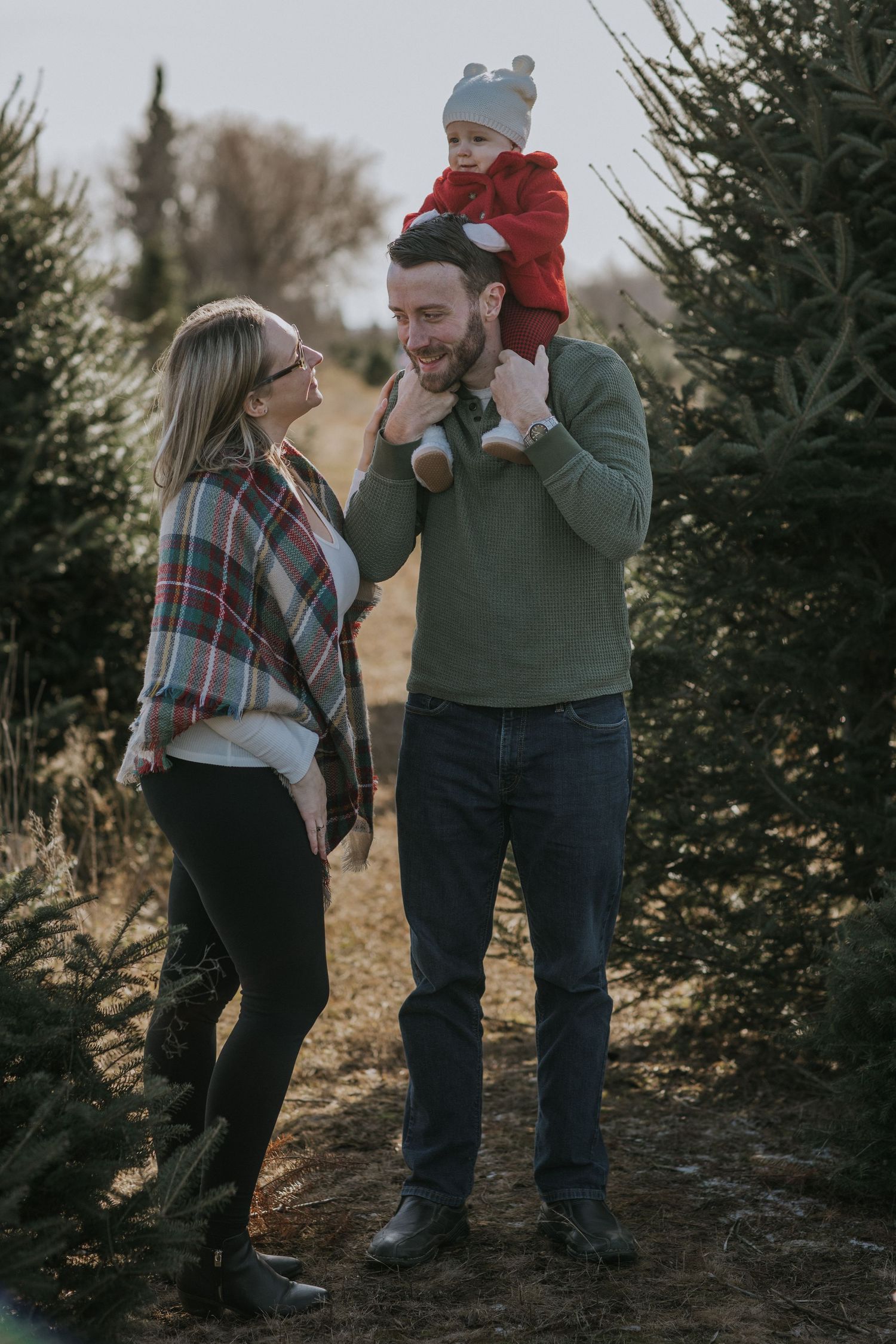 Family sharing playful moment among evergreen trees during outdoor photo session.