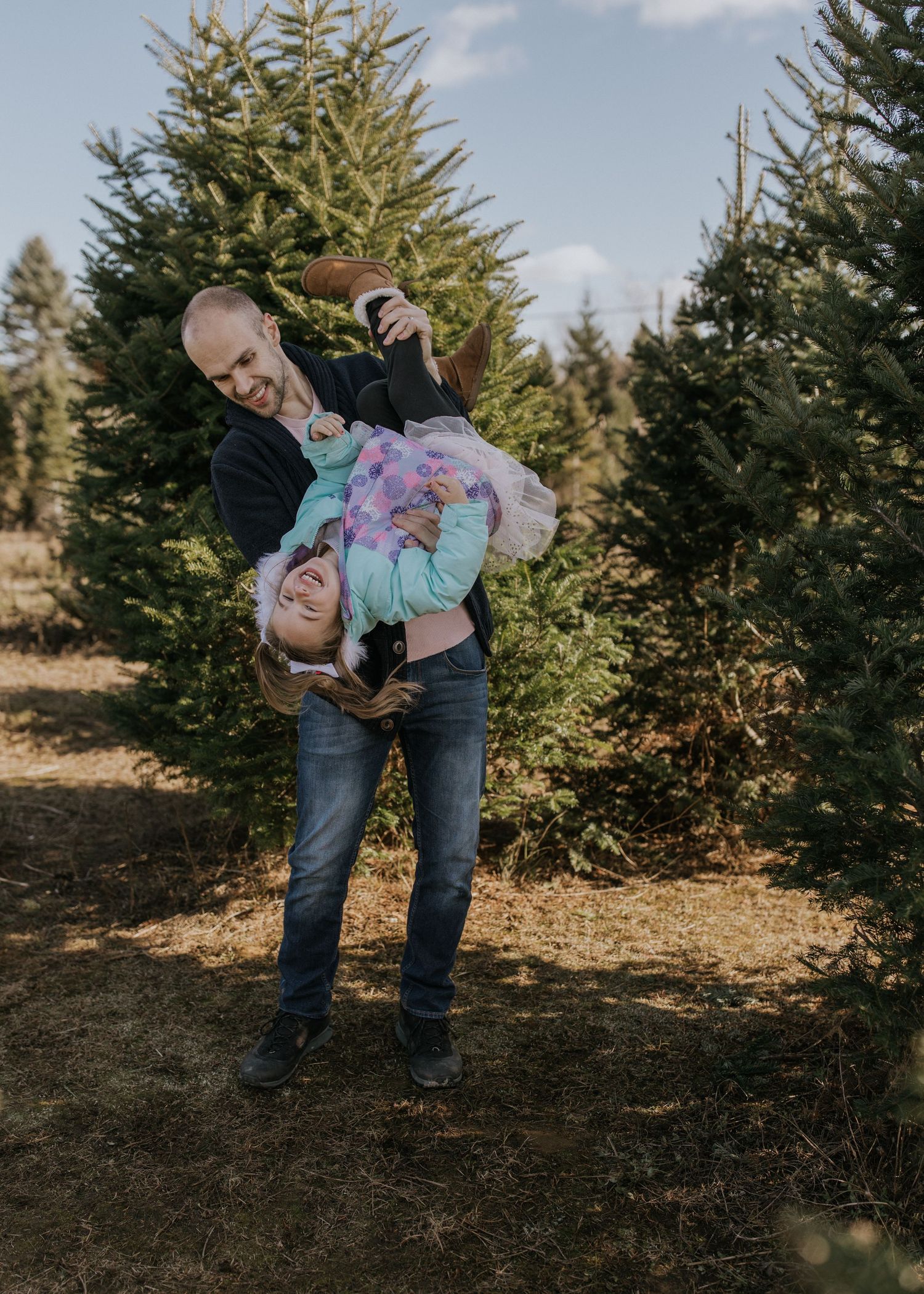 Playful family interaction among evergreen trees in natural outdoor setting.