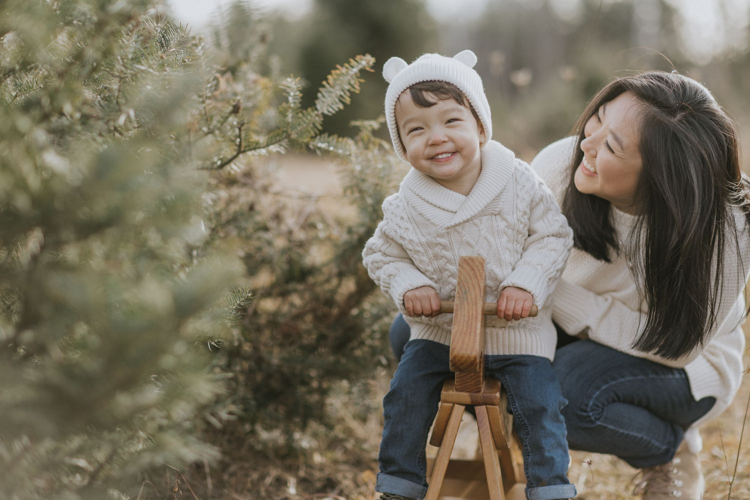 Candid family photo session showing tender moments in an outdoor setting with evergreen trees.