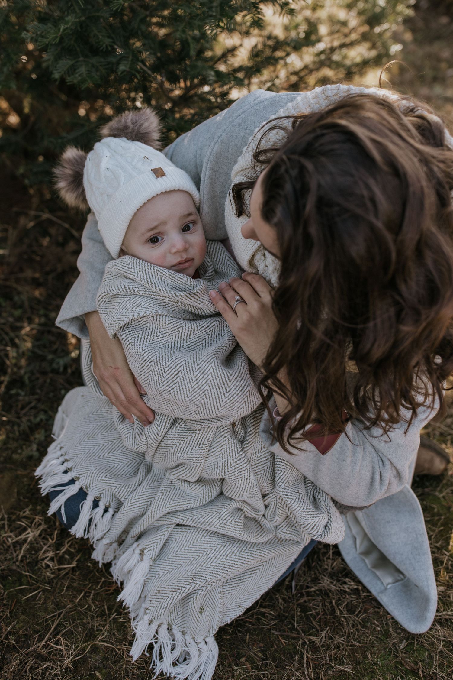 Cozy winter family moment wrapped in a knit blanket outdoors.