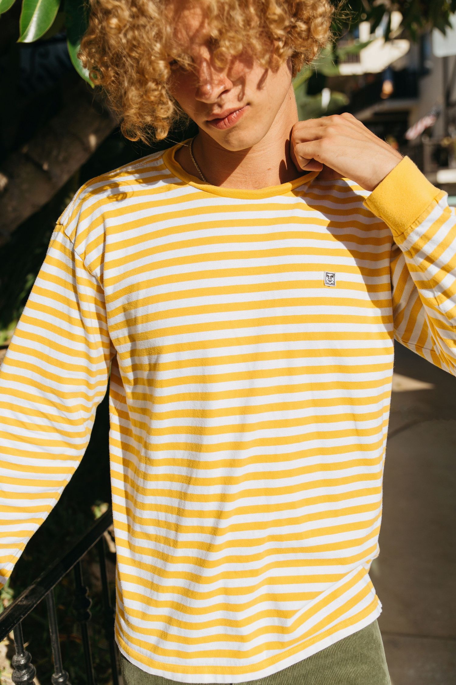Curly blonde male model wearing yellow and white striped tee from Obey brand, San Clemente beach fashion editorial