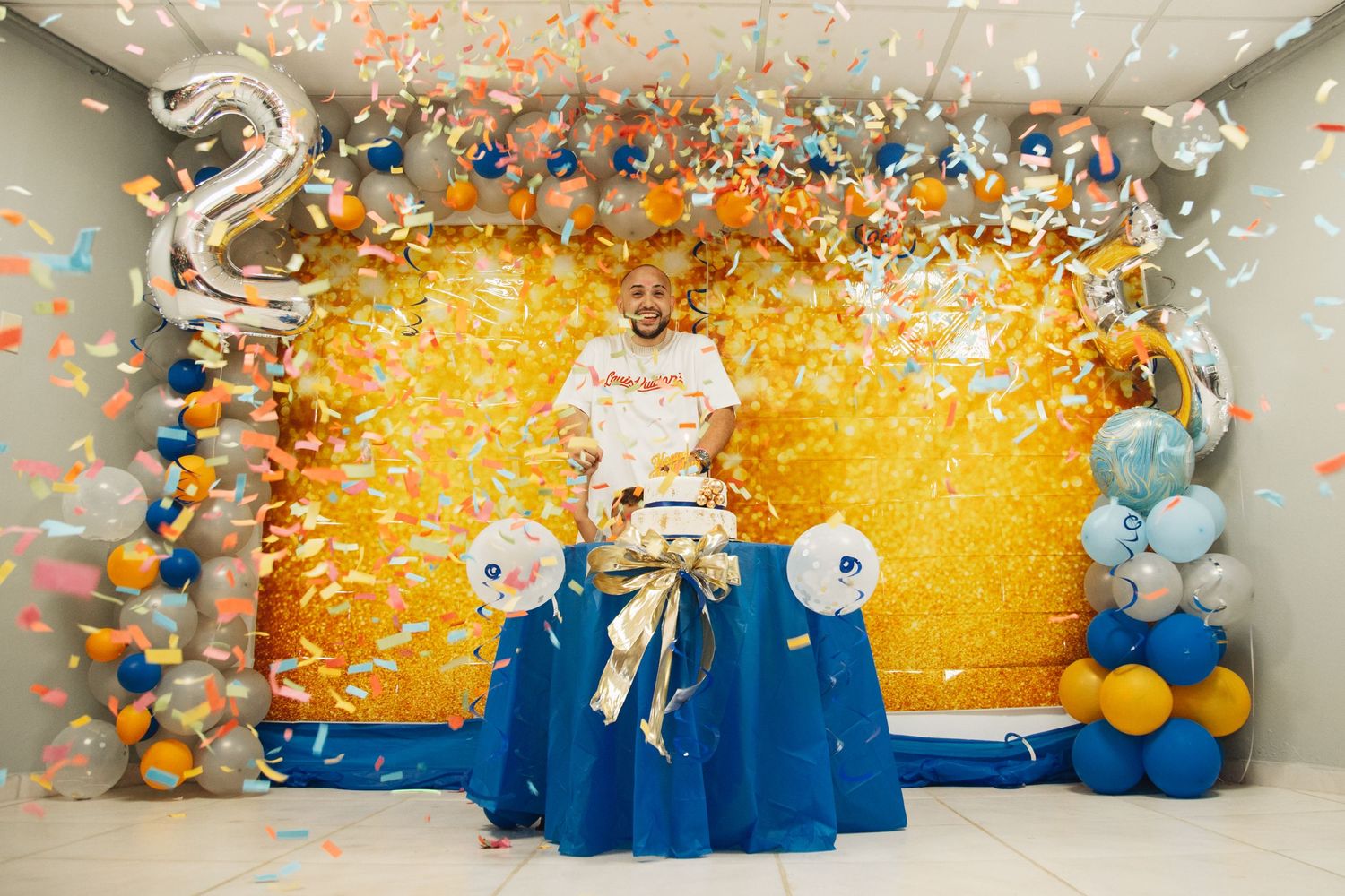 Birthday celebration setup with number 2 balloon, gold backdrop and blue decorative elements.