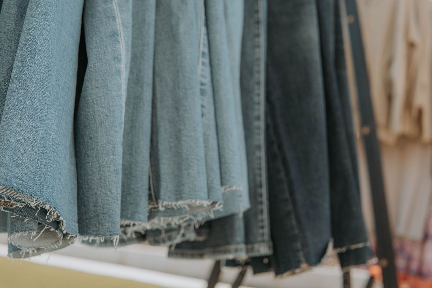 Row of light blue denim jeans hanging neatly on retail display rack.