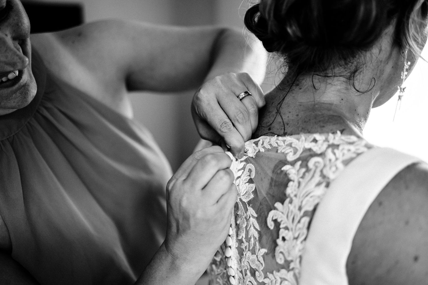 Close up black and white photo of dress buttons being fastened.