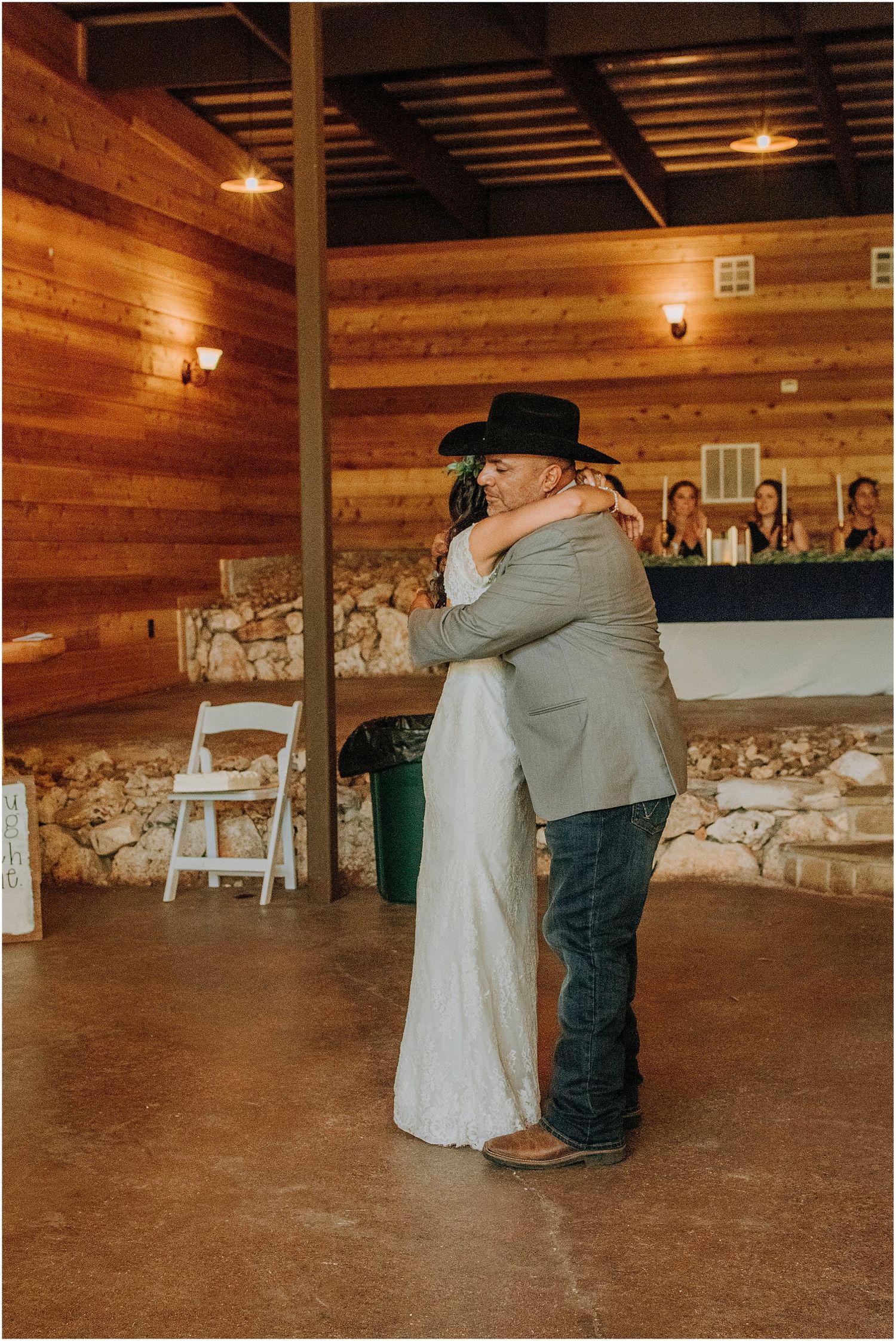 An emotional embrace during a wedding celebration in a rustic wooden barn venue.