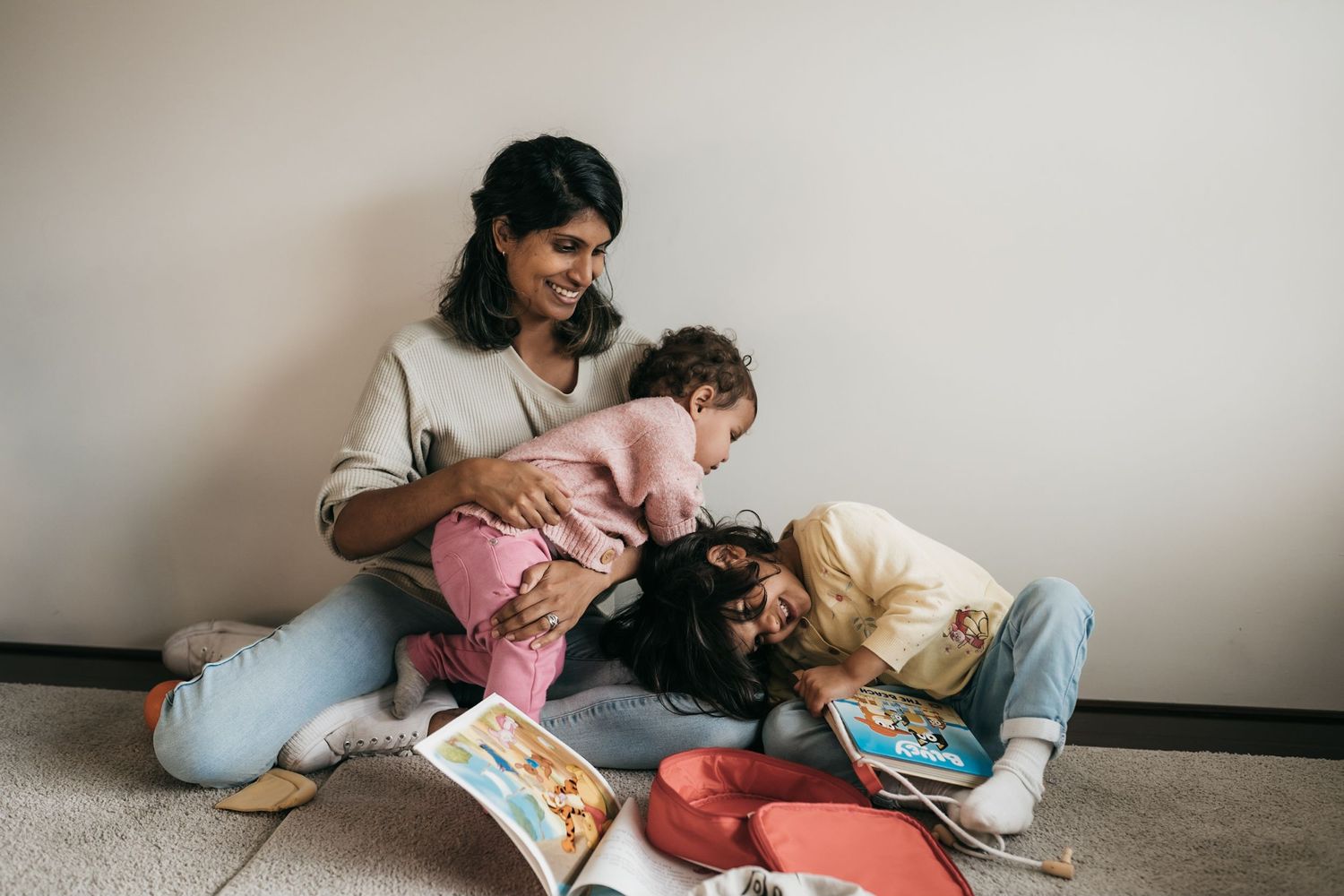 A mother reading with her two daughters in their home