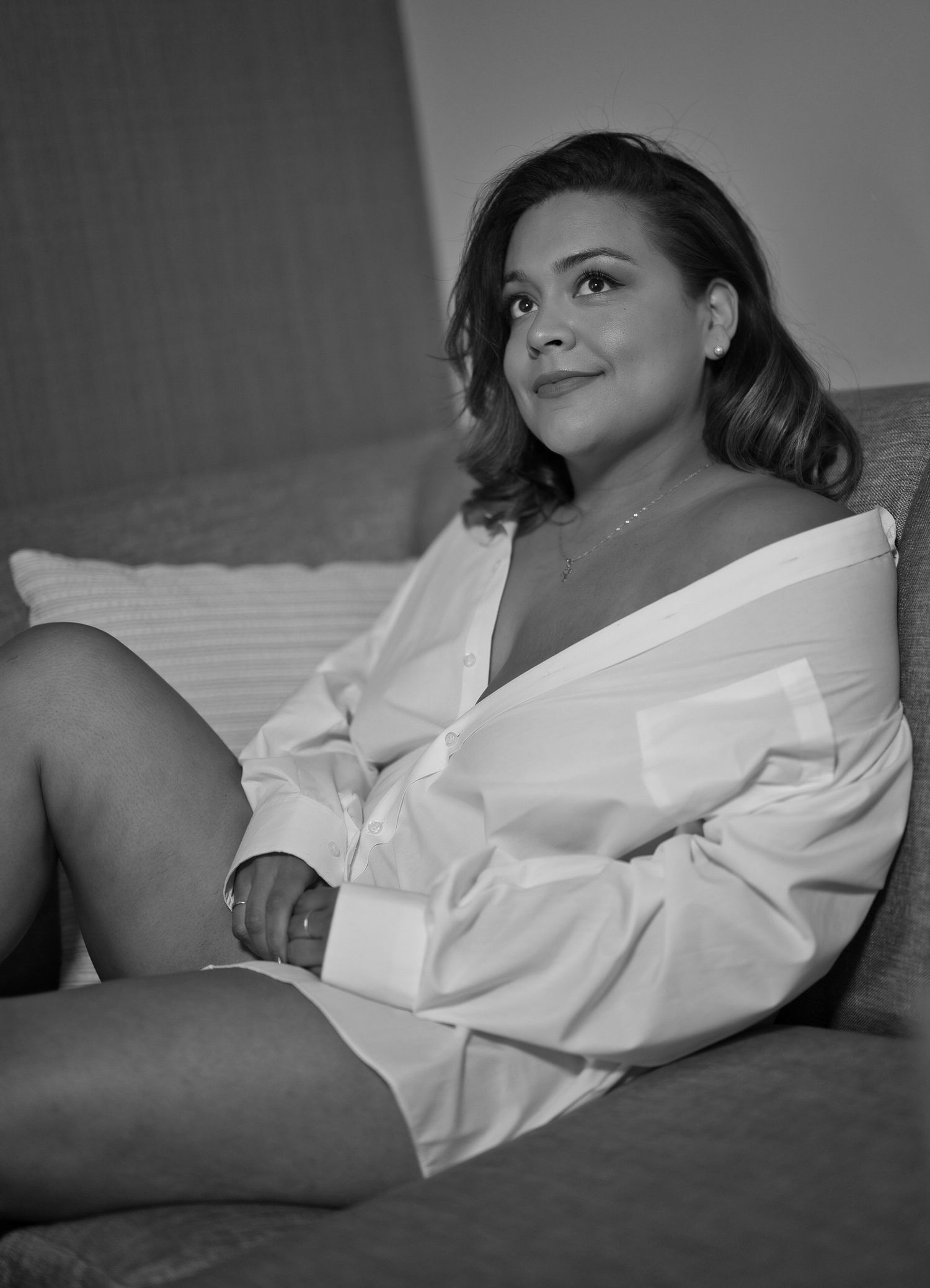 Artistic black and white photograph of a person in white robe sitting casually.