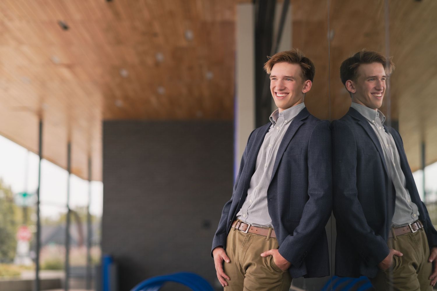 senior from lake ridge high school leaning against reflective surface in nice suit jacket looking away from camera