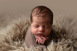 newborn chin on hands, newborn portrait.  Newborn photo session in brown swaddle