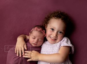 newborn girl photography, big sister with newborn sister, magenta newborn photography backdrop
