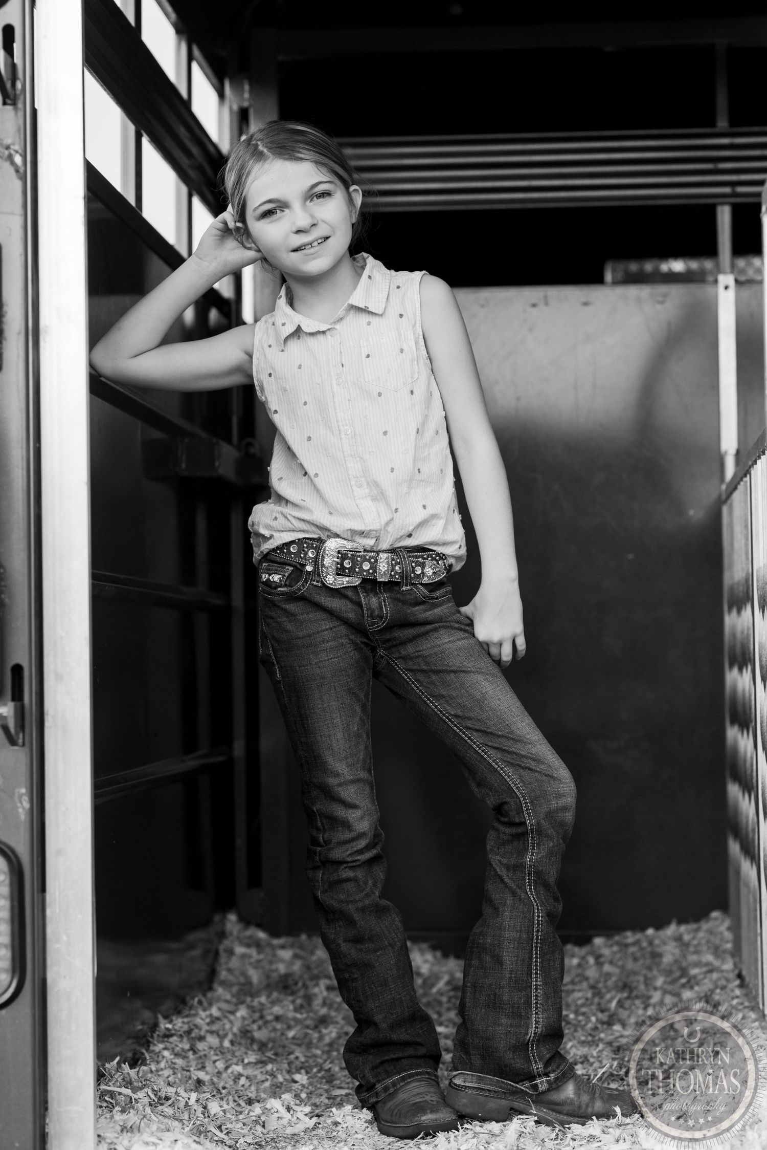 Black and white portrait of a young person posing in a rustic barn setting.