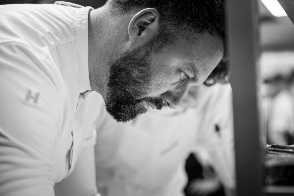 Professional kitchen scene with cook at work in white chef coat.