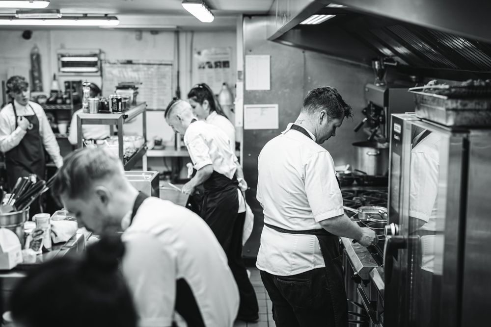 Black and white image of busy restaurant kitchen during service.