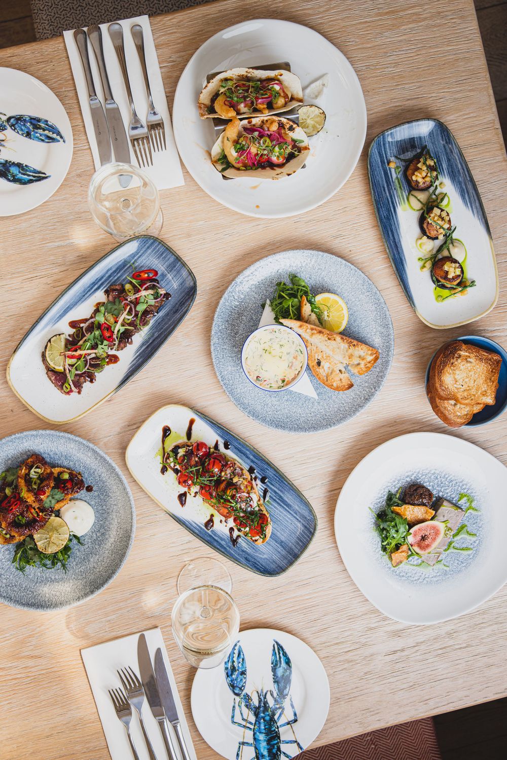 Overhead view of elegant plated dishes and table settings with seafood motif.