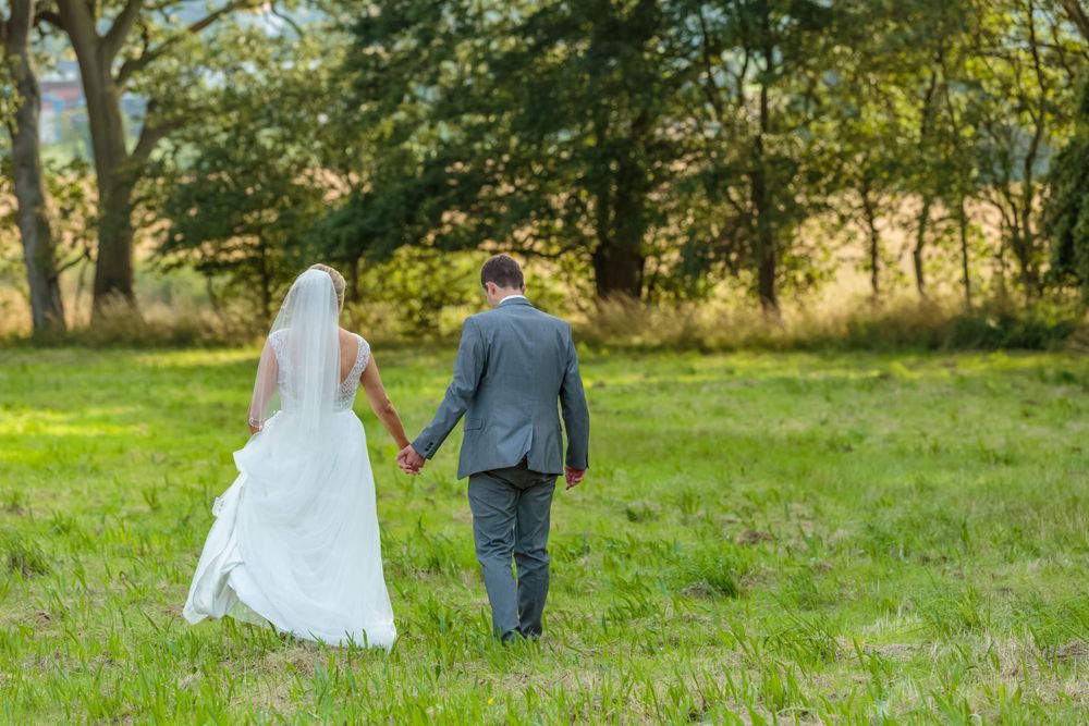 bride and groom walk hand in hand in the country grounds at west tower exclusive wedding venue