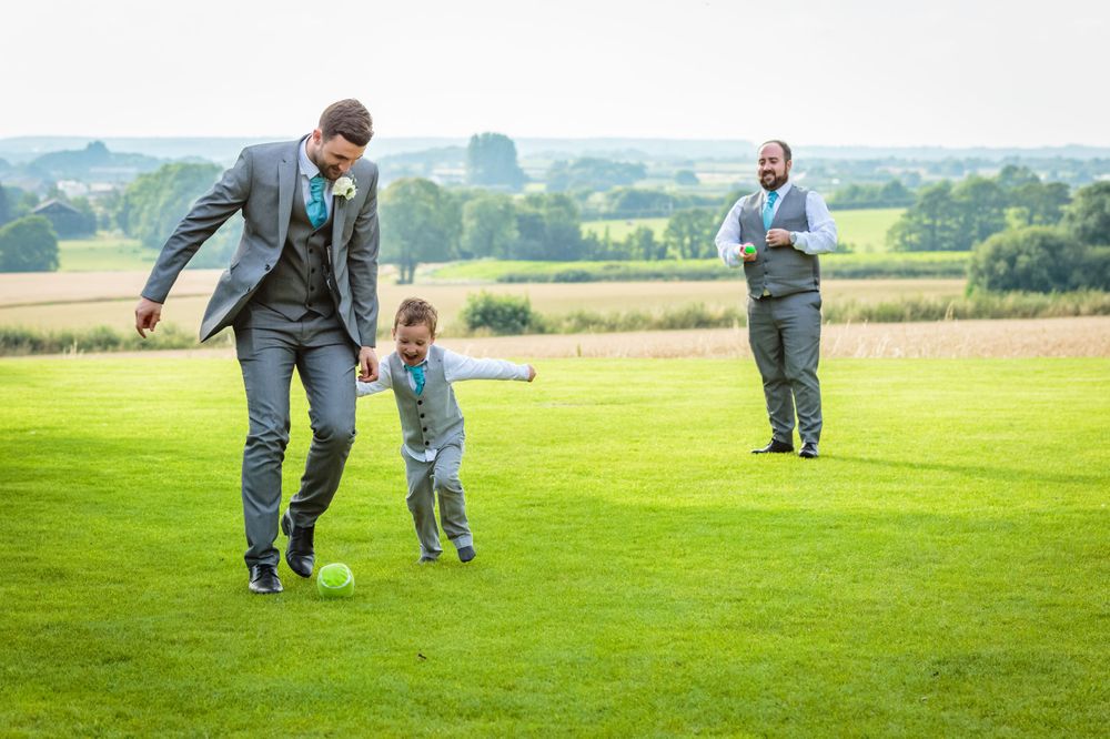 pageboy playing football with the best man tries to get the ball off him