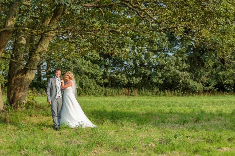 bride and groom posed her hands on his shoulder under a tree in the country grounds at west tower