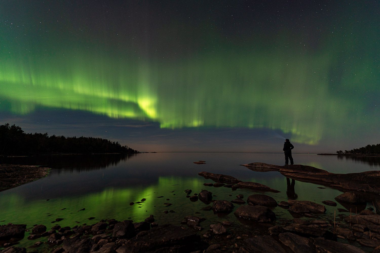 Fotograf Maria Karlsson kollar ut över Norrsken vid Vänerns kant strax utanför Hällekis, himlen är helt upplyst