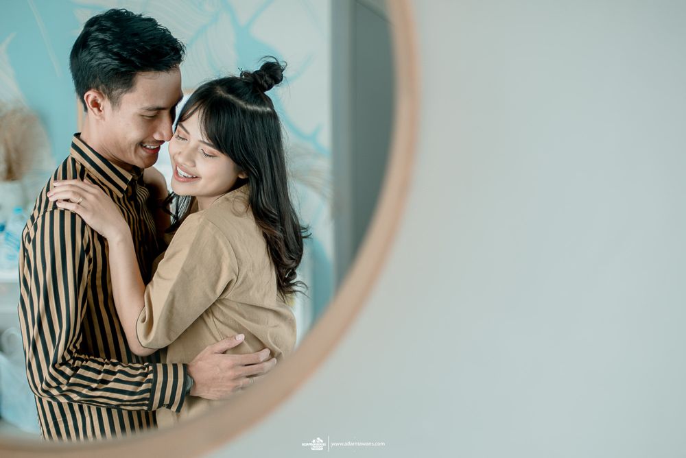 Romantic embrace captured in mirror reflection with soft muted tones and natural lighting.