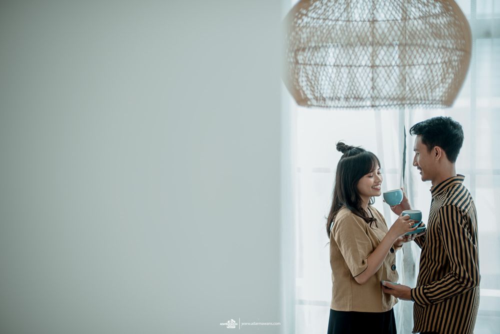 Couple standing under a woven pendant lamp in a minimalist interior with soft lighting.