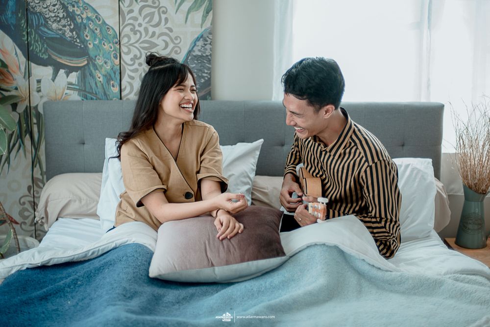 Candid moment of joy shared on a bed with blue bedding and decorative pillows.