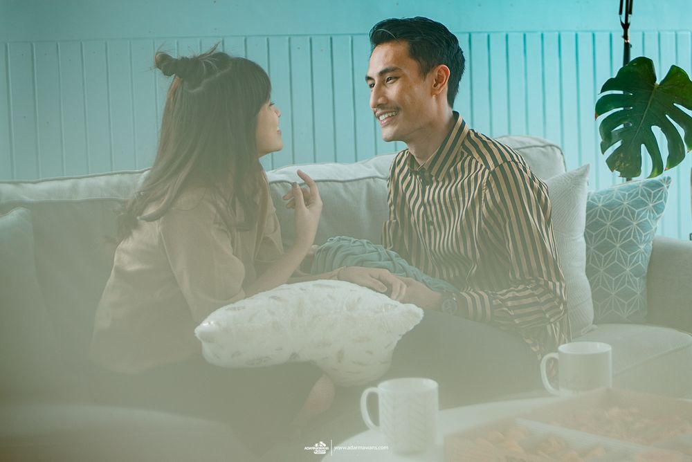 Couple sharing an intimate conversation on a couch with soft atmospheric lighting and a monstera plant.