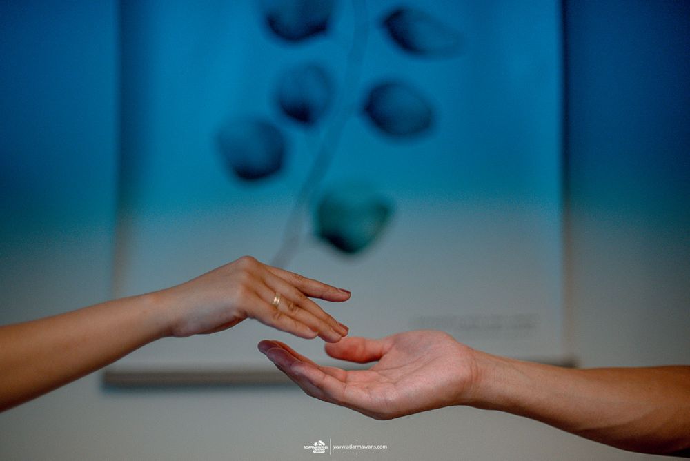 Two hands reaching toward each other against blurred blue background with circular patterns.