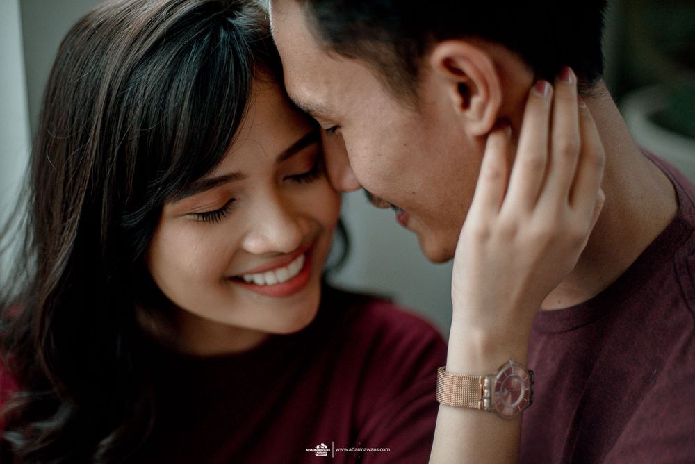 Couple in burgundy sharing an intimate close-up moment with gentle touches.