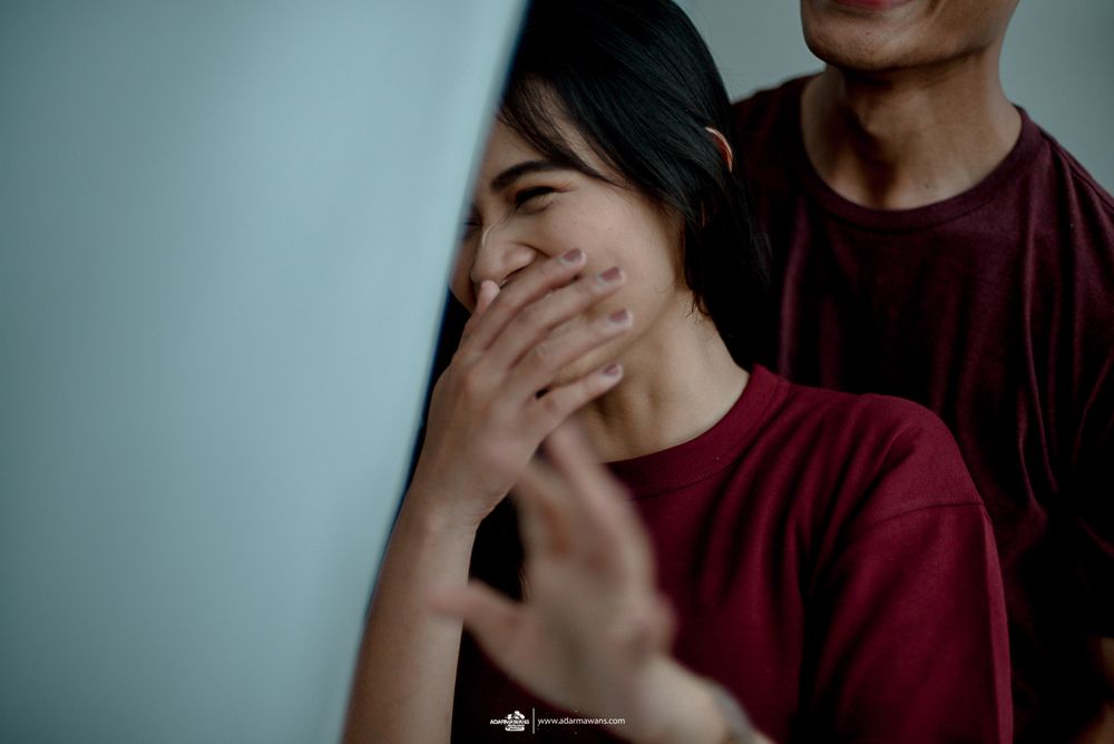 Couple sharing a playful candid moment as she covers her smile.