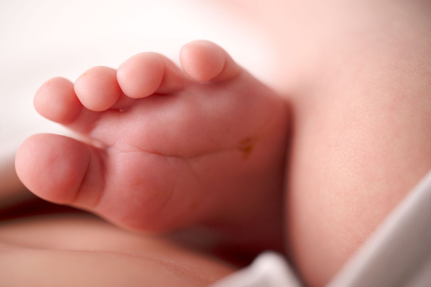Close-up of a newborn baby's tiny foot showing delicate toes.