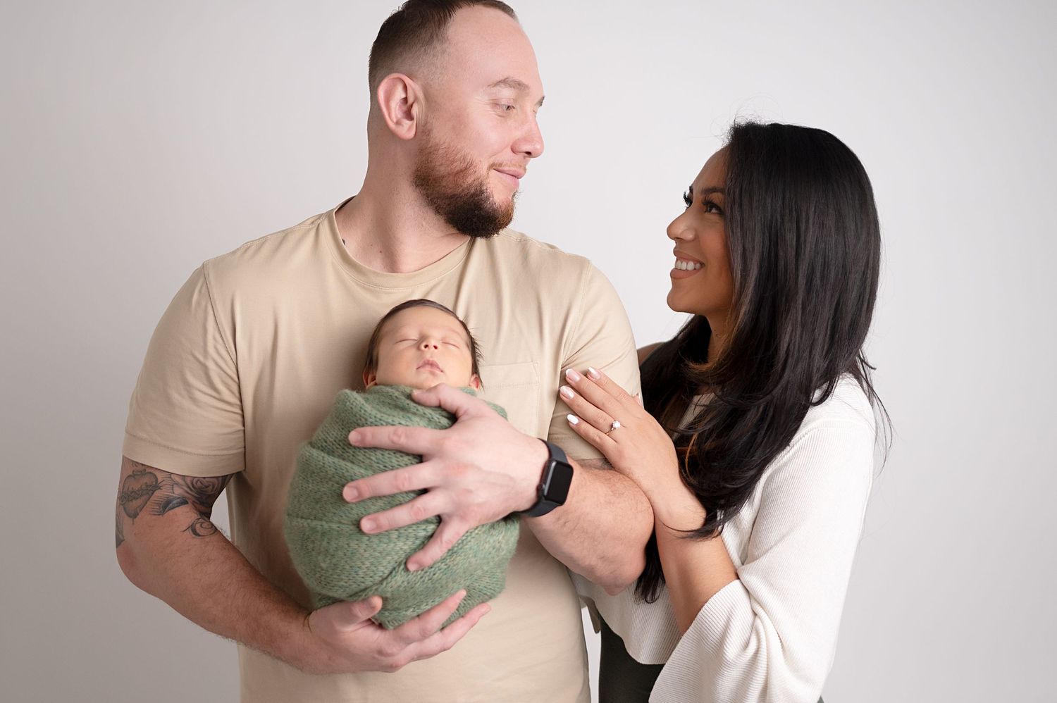 Lifestyle newborn photography session captures sweet family moments against clean white background.