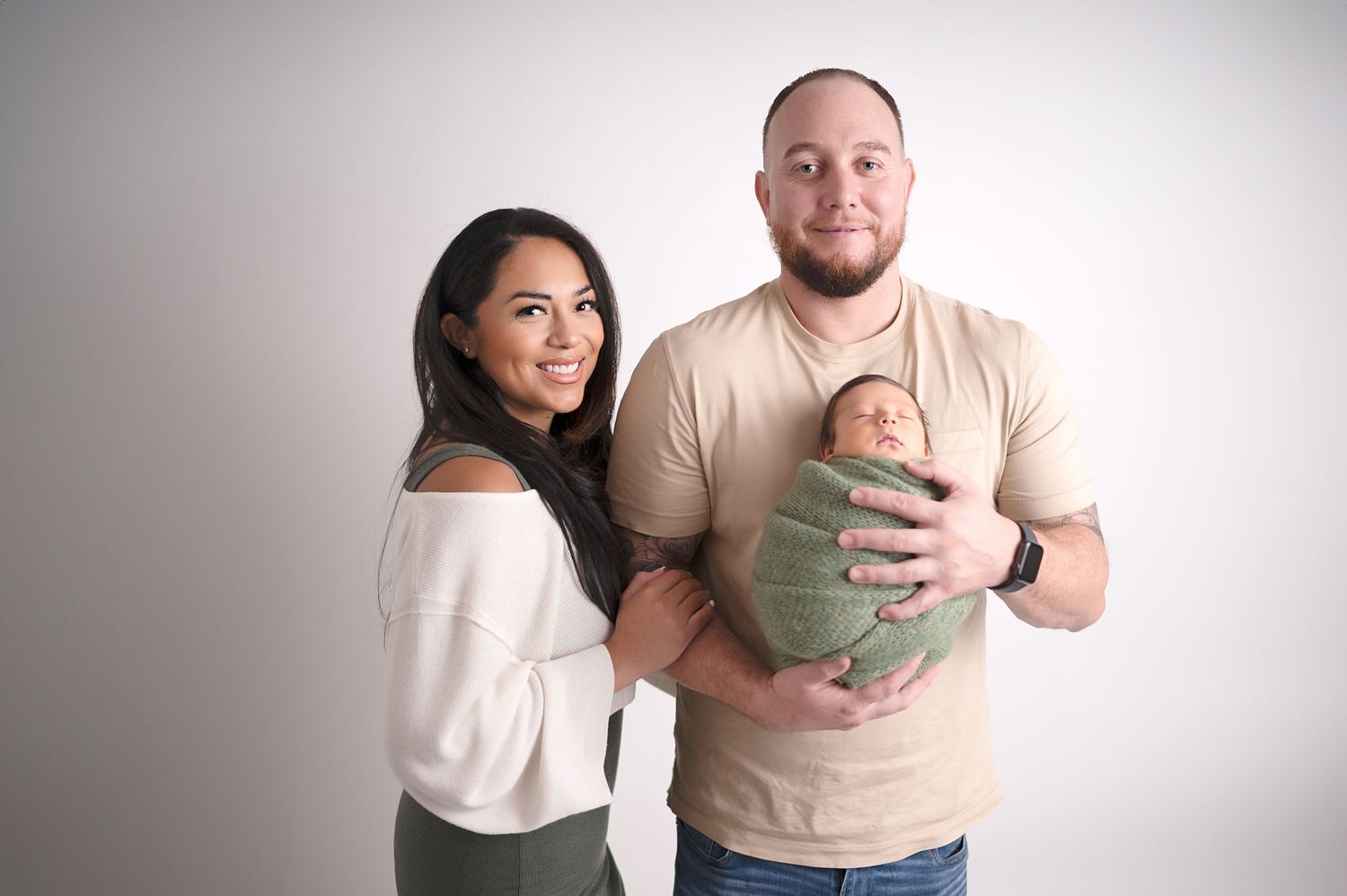 Candid family portrait session showing joyful moments with newborn in minimalist studio setting.