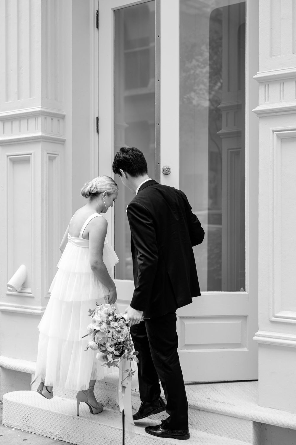 A black and white wedding photo showing architectural details and romantic moments.
