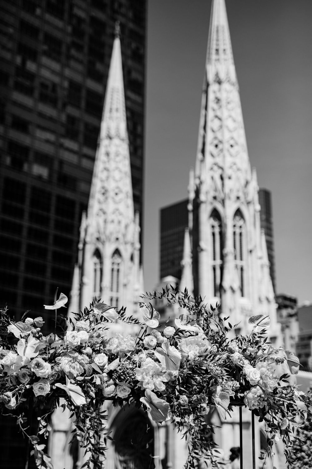 Black and white image of church spires with floral arrangements in foreground.