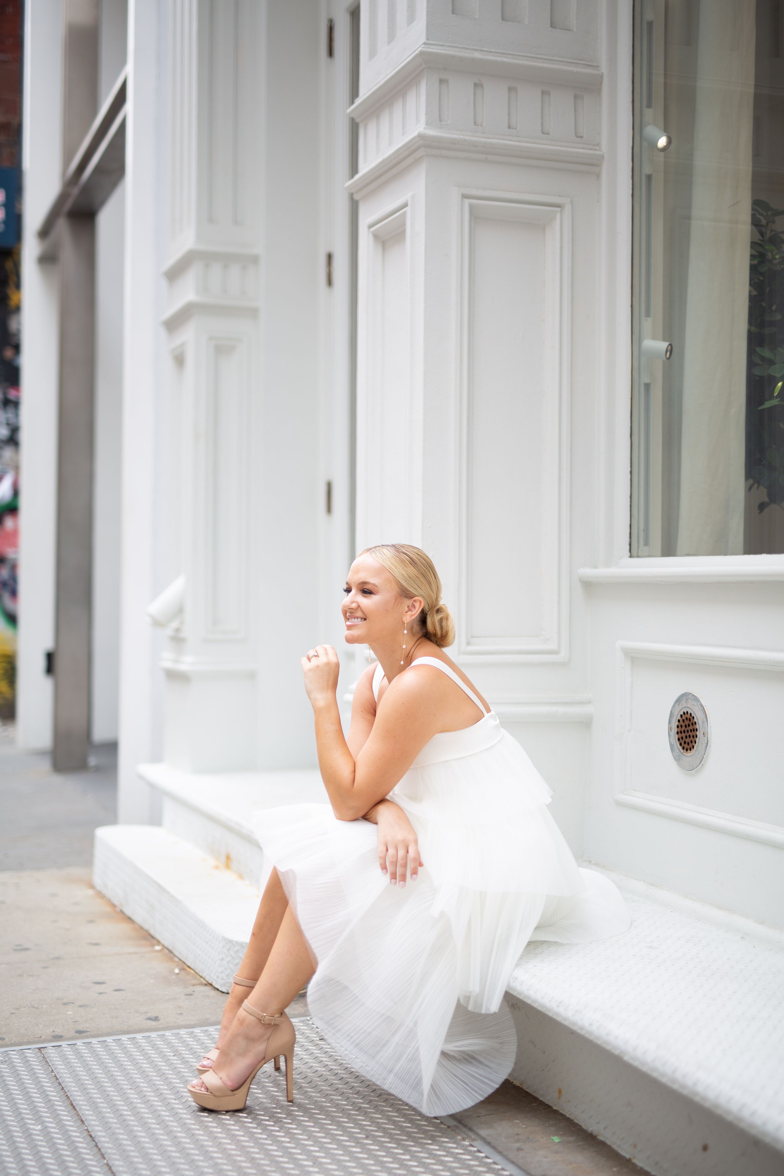 An elegant bridal portrait against white architectural details in soft lighting.