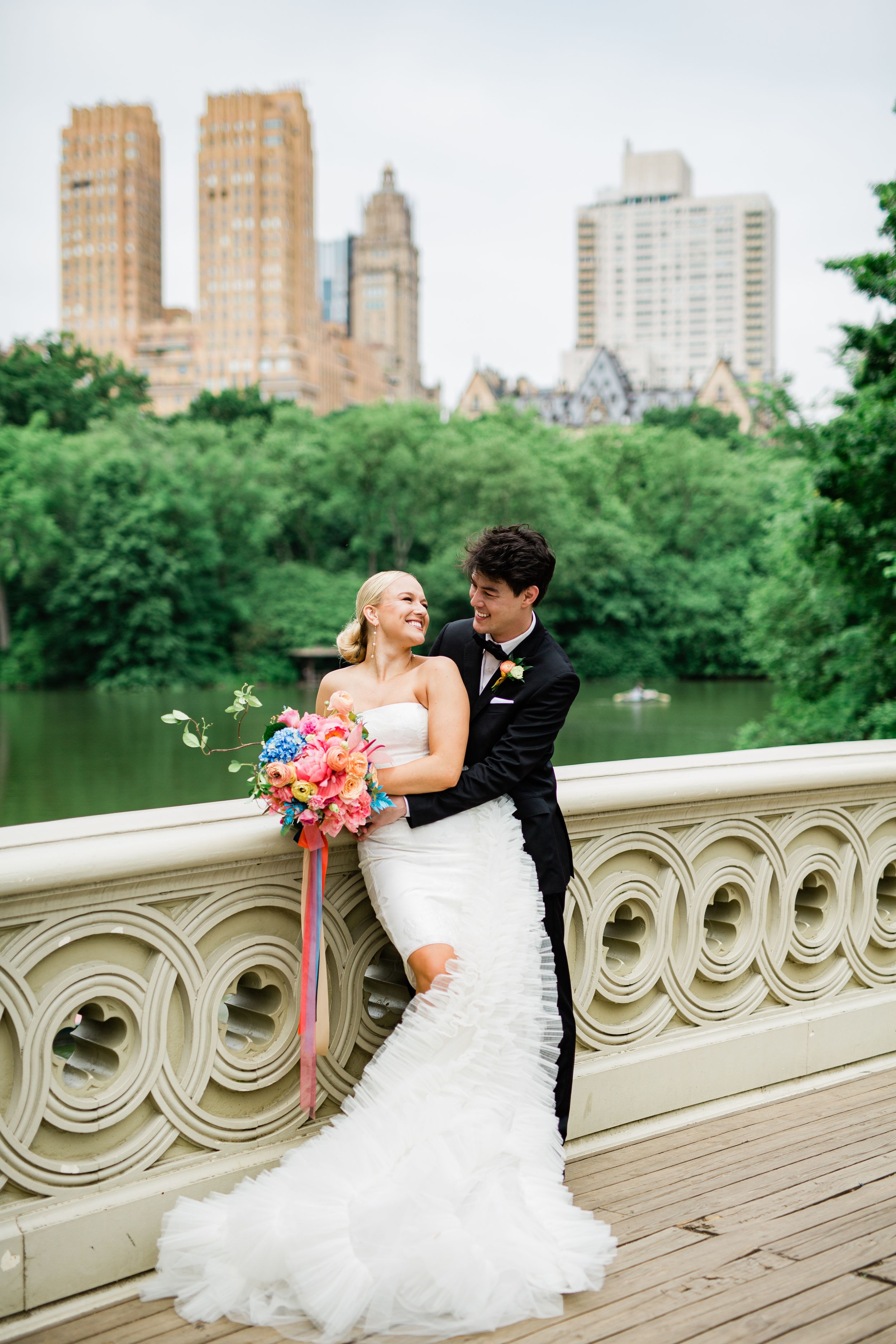 A romantic wedding moment captured on Bow Bridge in Central Park with the NYC skyline in the background.