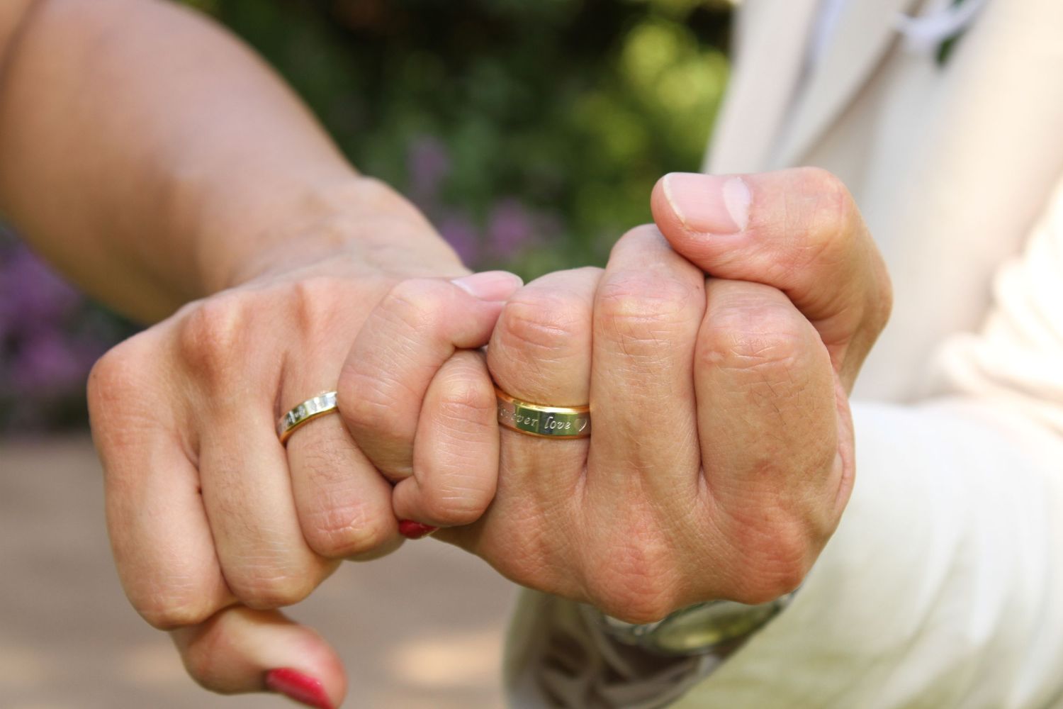 Close-up shots of wedding rings displayed on hands against natural lighting.