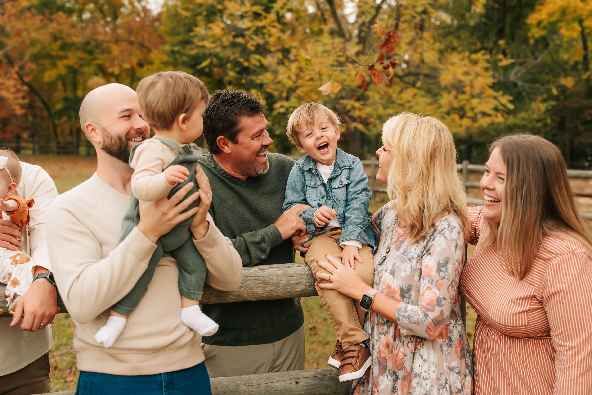 Group of people sharing joyful laughter during outdoor gathering in fall setting.