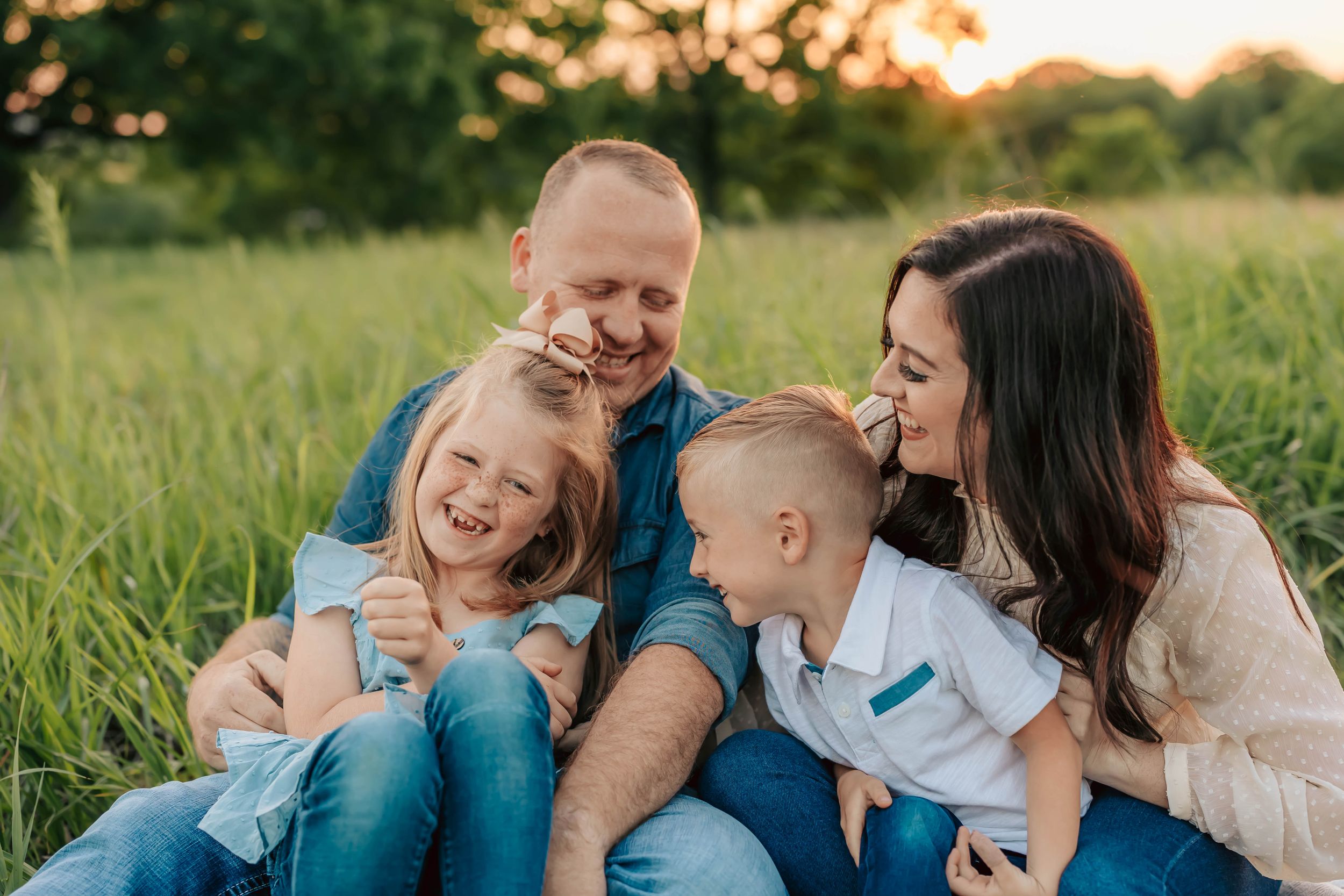 Happy family sharing joyful moment together on grass at sunset.