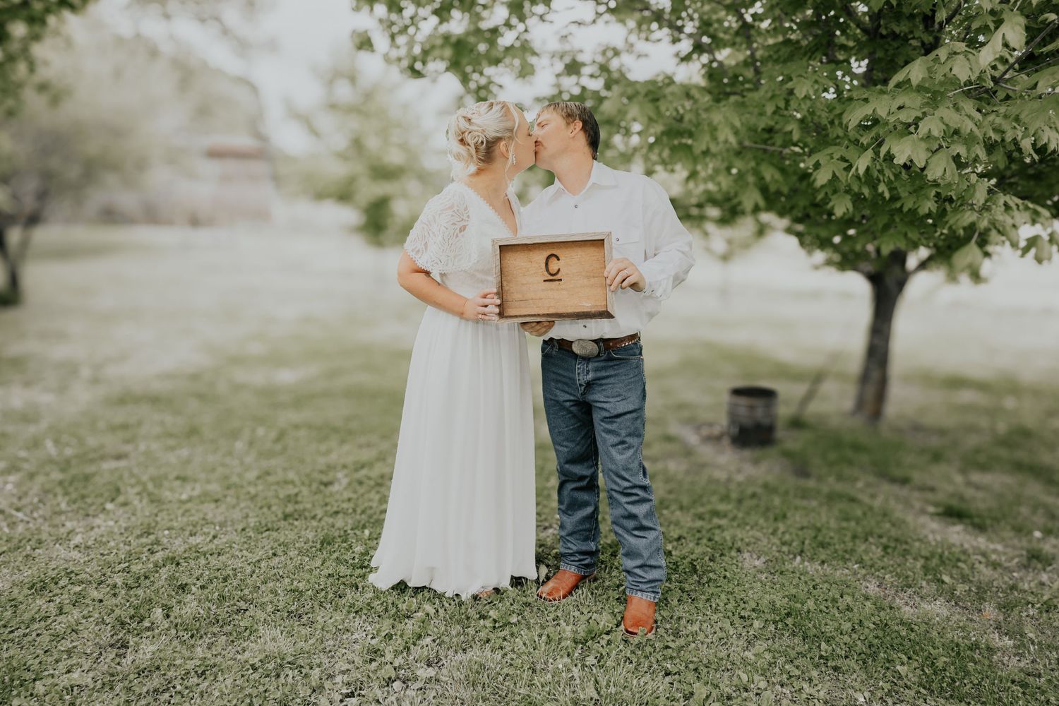 Couple embracing while holding wooden boxes in an orchard setting.