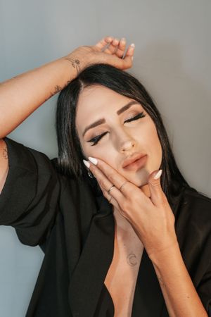 Model in black posing with hands in artistic portrait series.