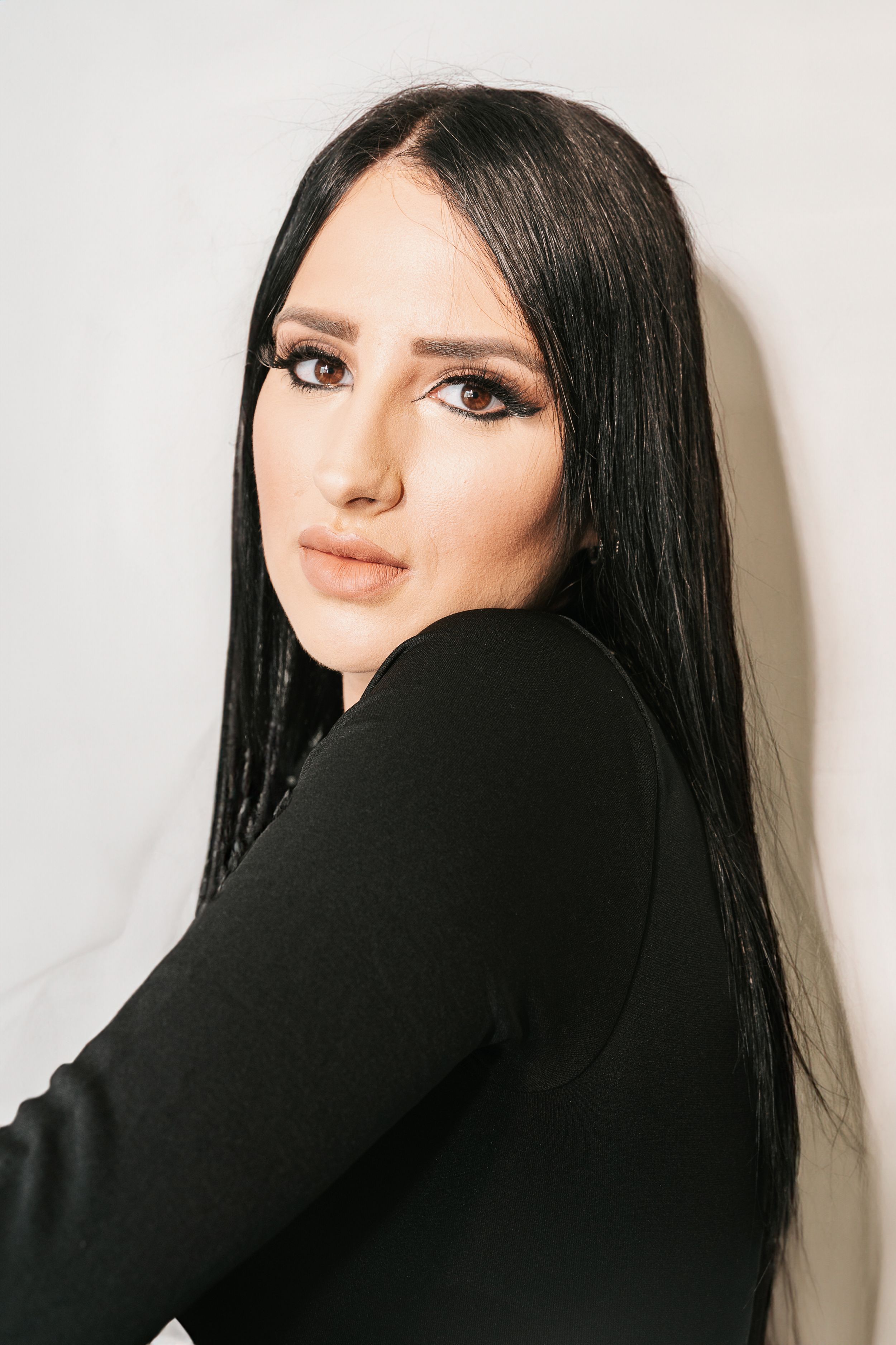 Fashion portrait series with model in black sweater against white background.