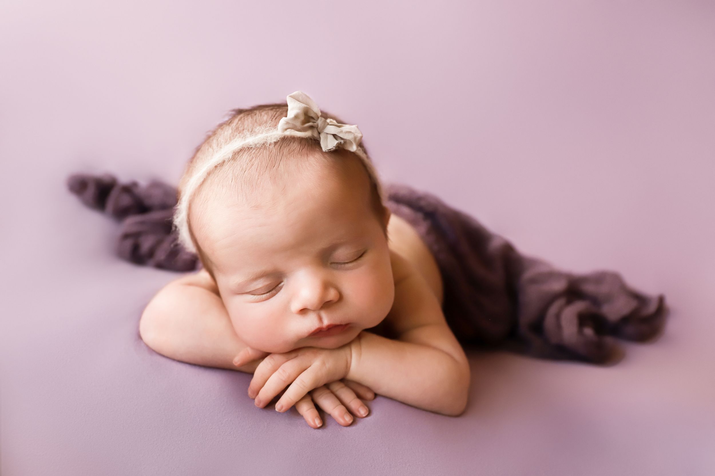 fine art newborn studio portrait with baby girl in purple chin on hands