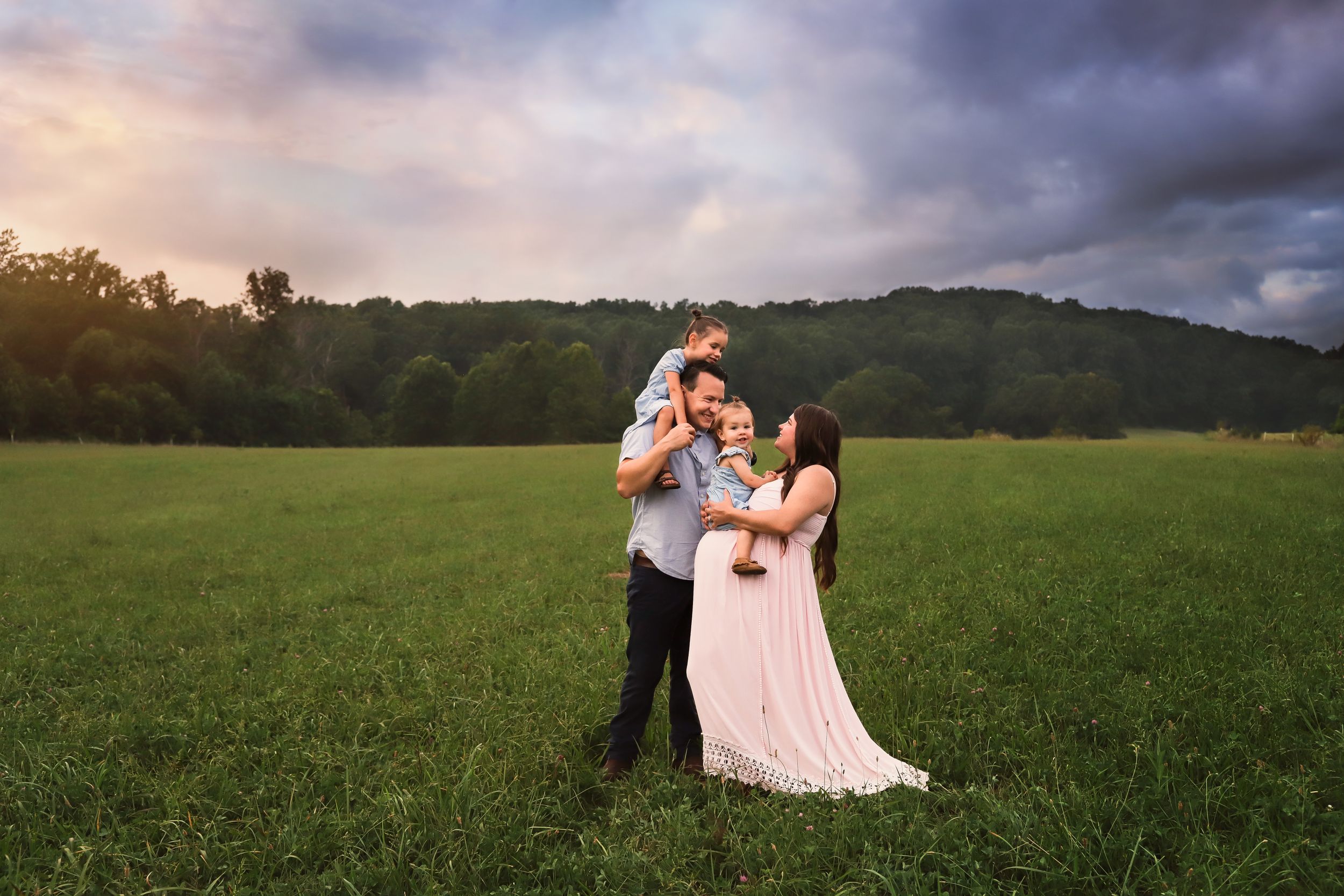 fine art maternity/family outdoor portrait in field with cloudy sky