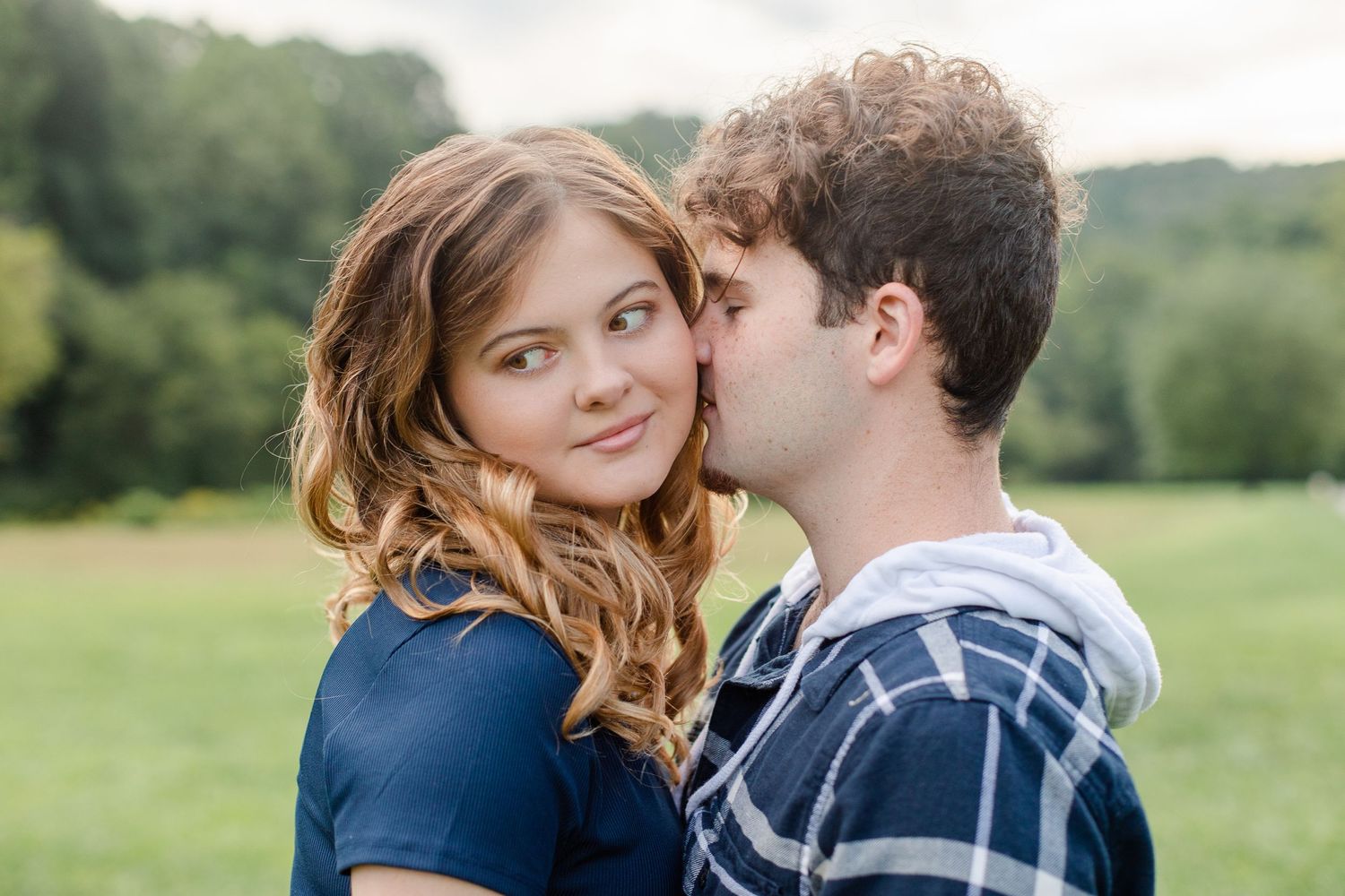 Intimate couple portraits in a lush green field during golden hour.
